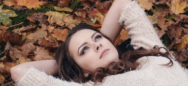 Kvinna bland höstlöv, tittat upp mot himlen och utövar mindfulness